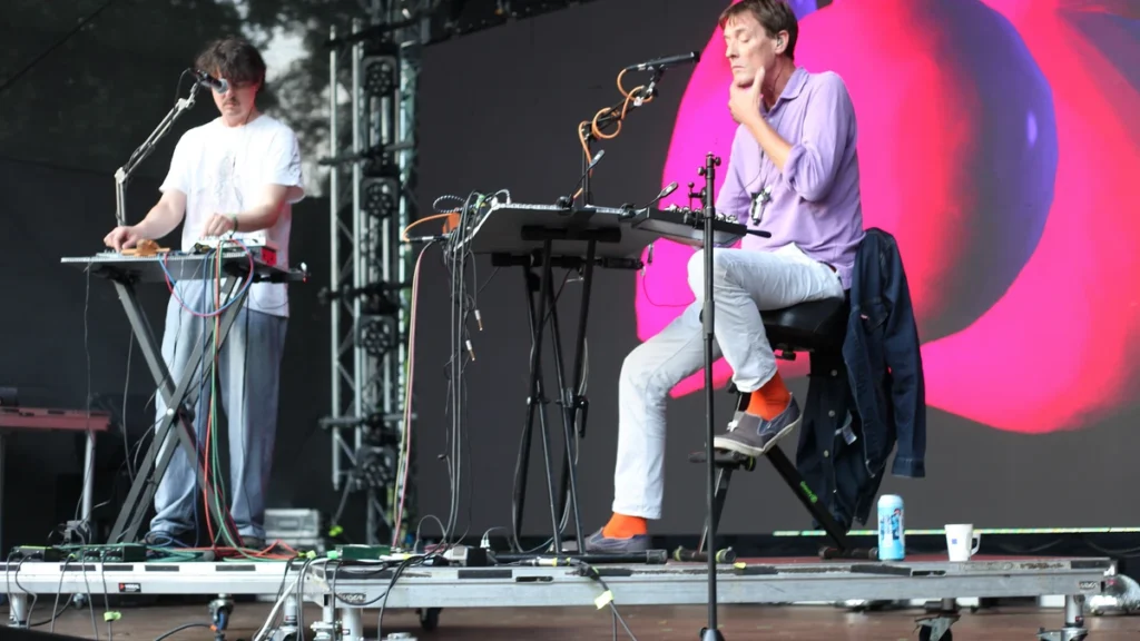 Panda Bear and Sonic Boom performing behind keyboards on a festival stage