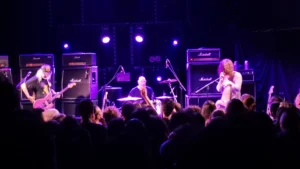Dinosaur Jr on stage in front of stacked amplifiers under purple lighting